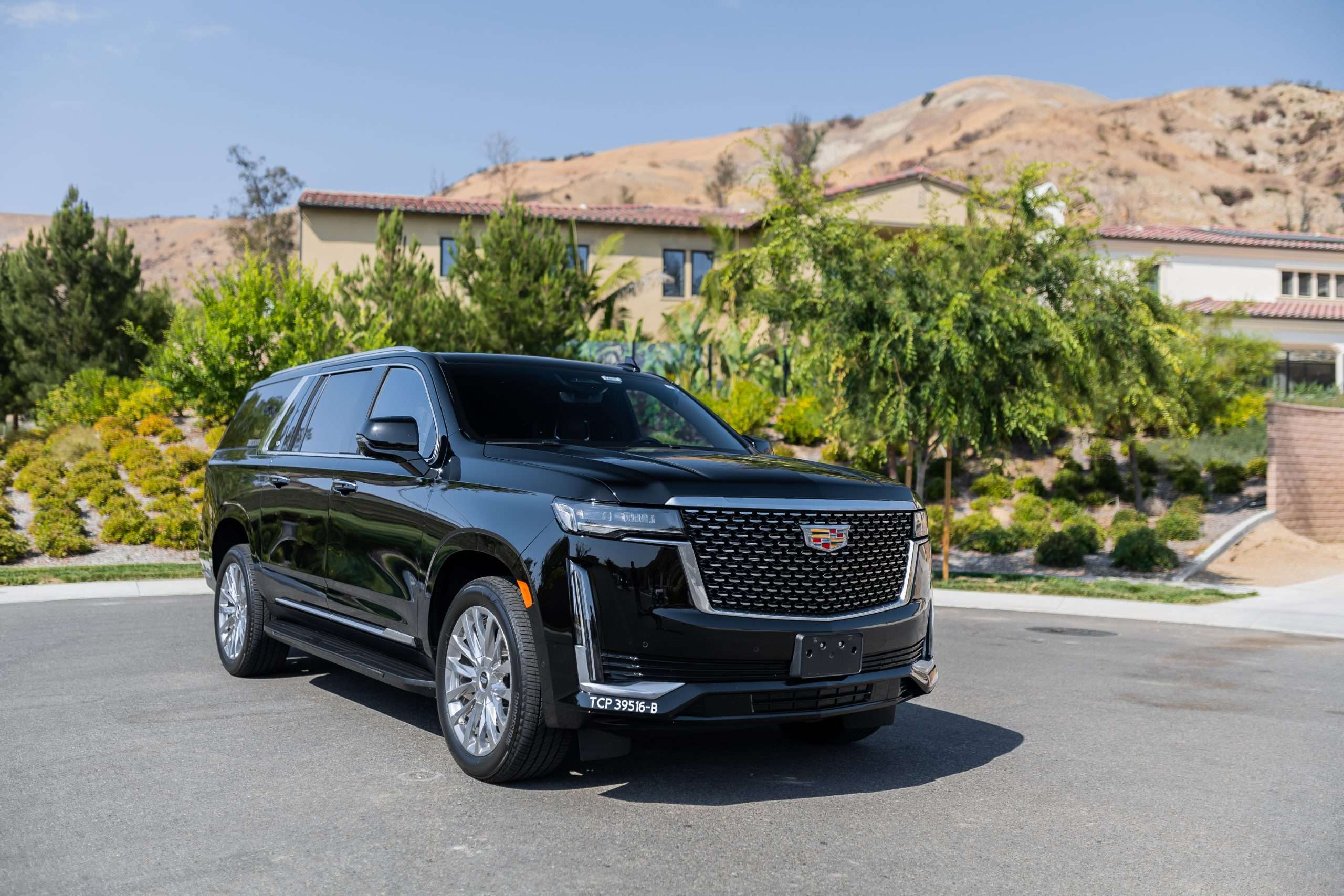 Black Cadillac Escalade in upscale residential area with hills